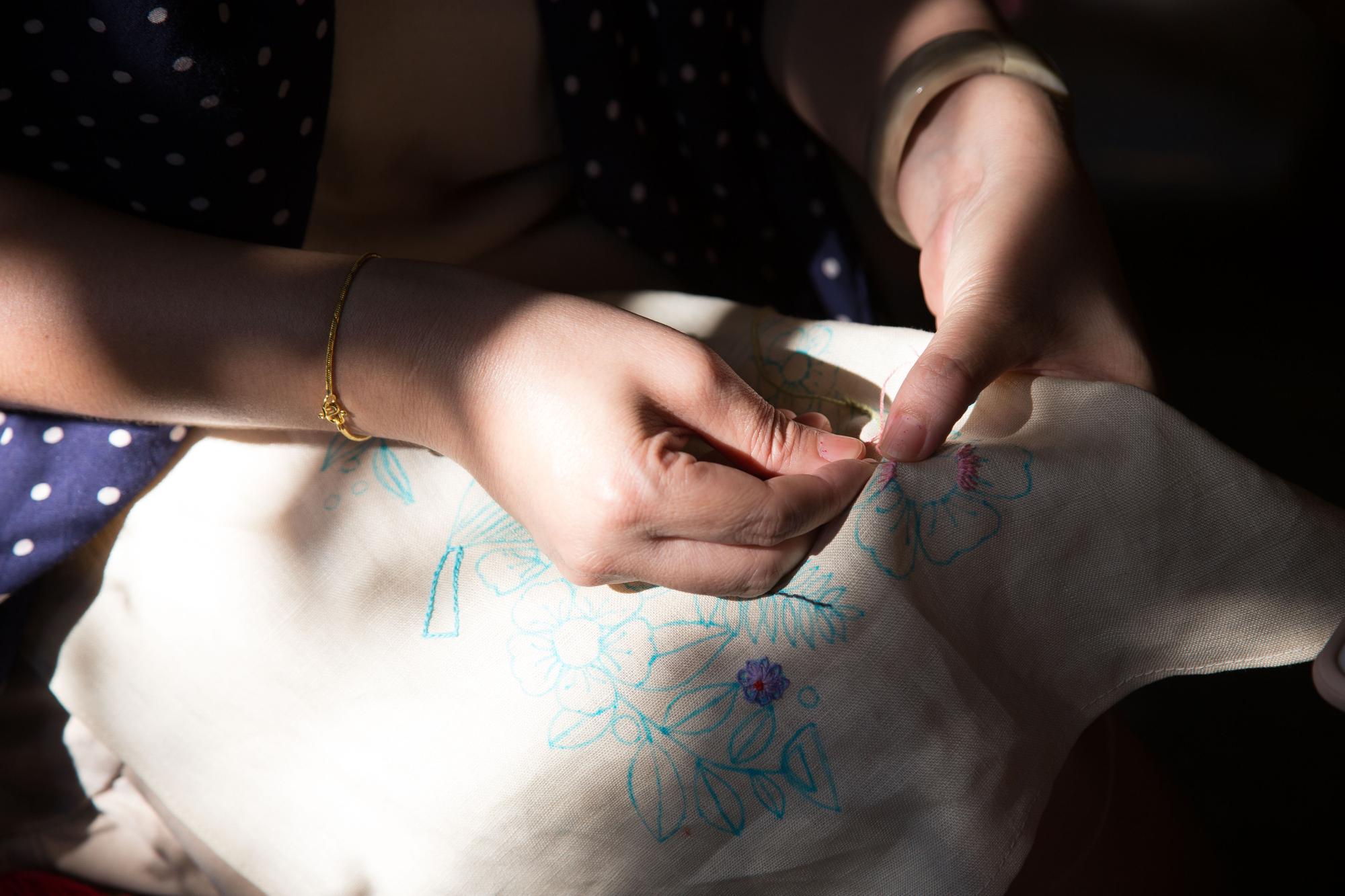 Detaliu ateliereu cu mâini lucrând broderie